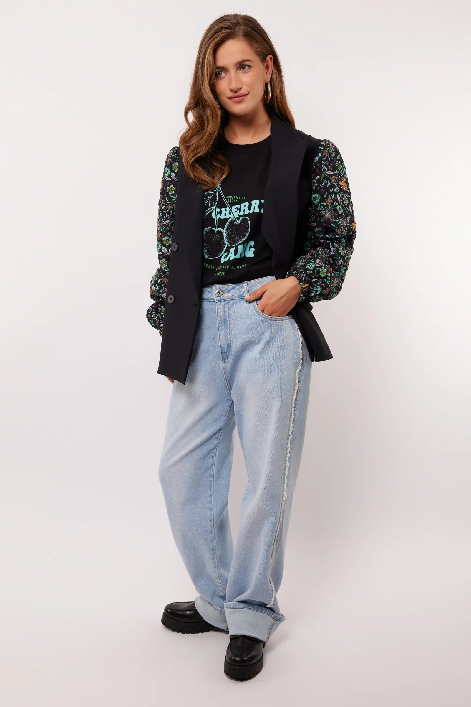 Model draagt de Fluresk Celin Pants in lichtblauw denim met een zwarte Cherry Gang top en gilet.