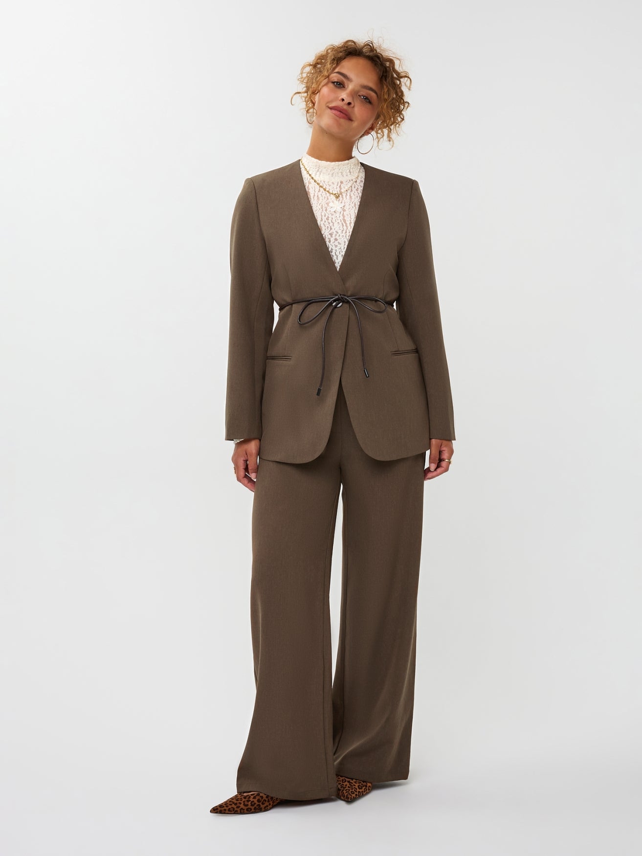 model draagt de ydence lexie blazer in de kleur mud met een zwart ceintuur. hieronder draagt ze de yade pants van ydence.