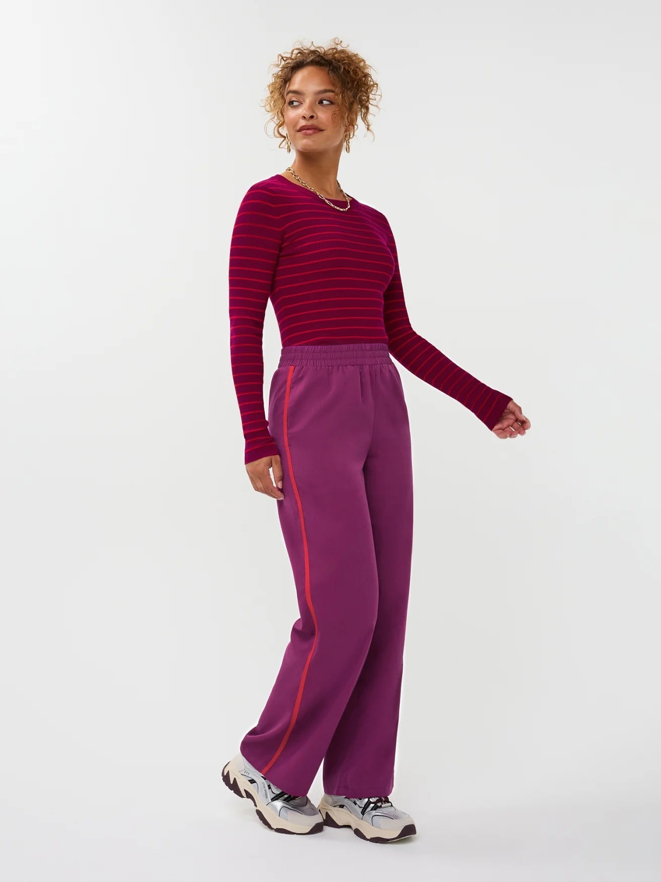 Model draagt de ydence knitted top devina met fuchsia en rode strepen. op de Zizi pants.