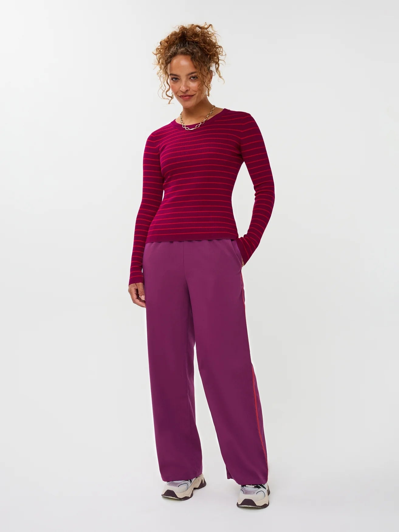 Model draagt de ydence knitted top devina met fuchsia en rode strepen.
