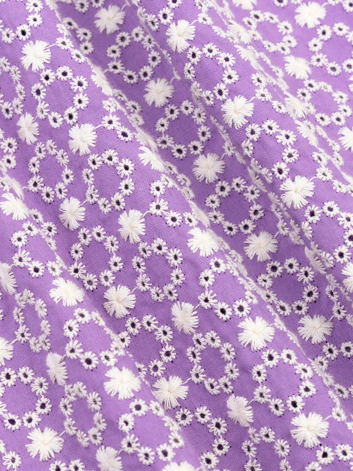 Detail van het lila katoen met wit broderie bloemenpatroon van de Mila top.