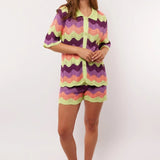 Model draagt de complete co-ord set met Rihanna Shorts en Whitney blouse van Fluresk – kleurrijke zomerse outfit in gehaakt zigzagmotief.