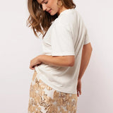 Zijaanzicht van het Soraya T-shirt gecombineerd met een glanzende bloemenrok.