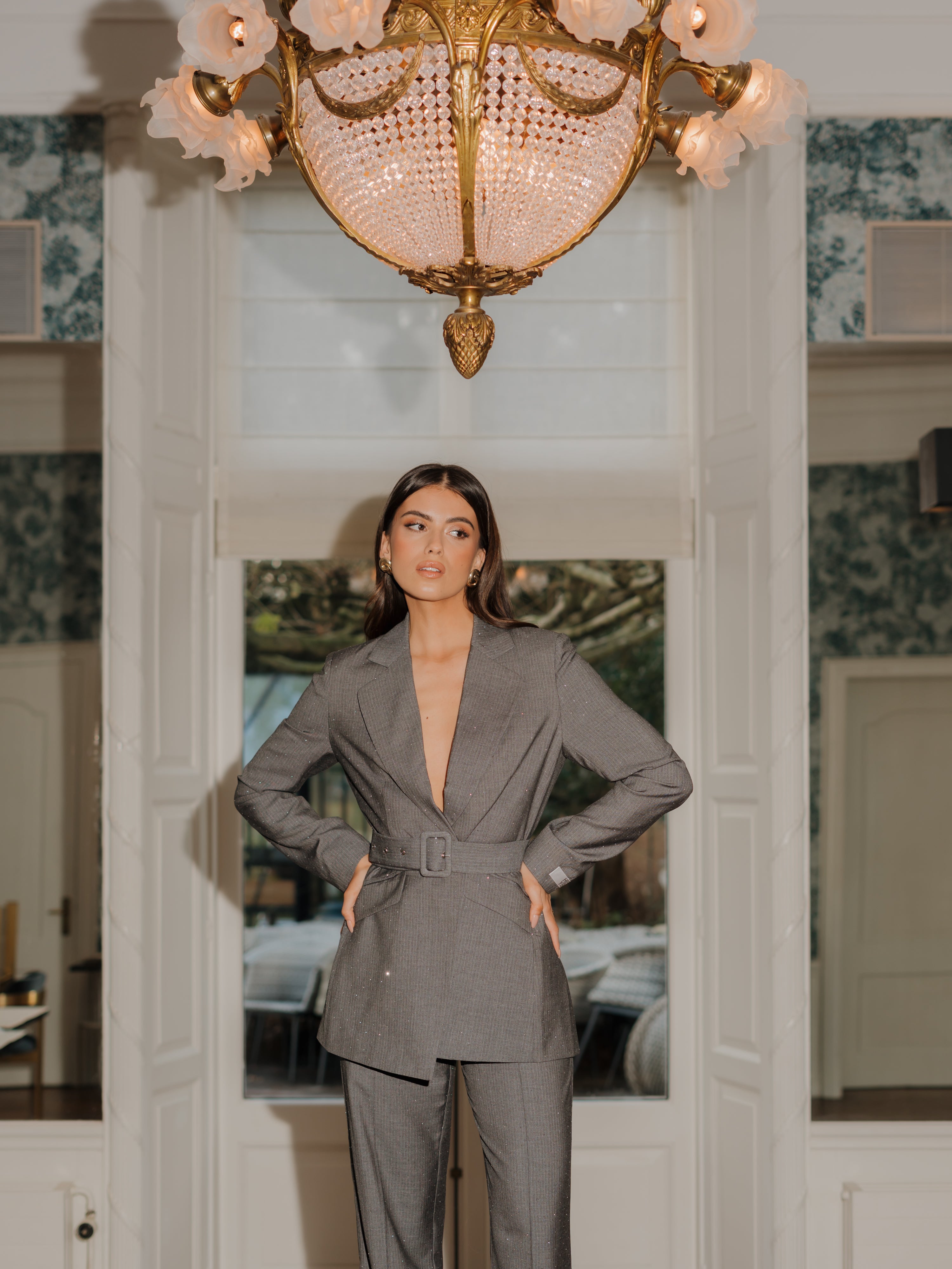 model draagt de Ann Blazer en de Ann trousers van heyb club in grijs met glitters en ceintuur.