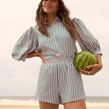Model draagt de Annie blouse en Belle short van Ydence als co-ord set op het strand – zomerse look met streepjesprint.
