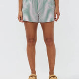 Model draagt de Belle short,een luchtige wit-lila gestreepte short met elastische tailleband van Ydence, ideaal voor het strand.