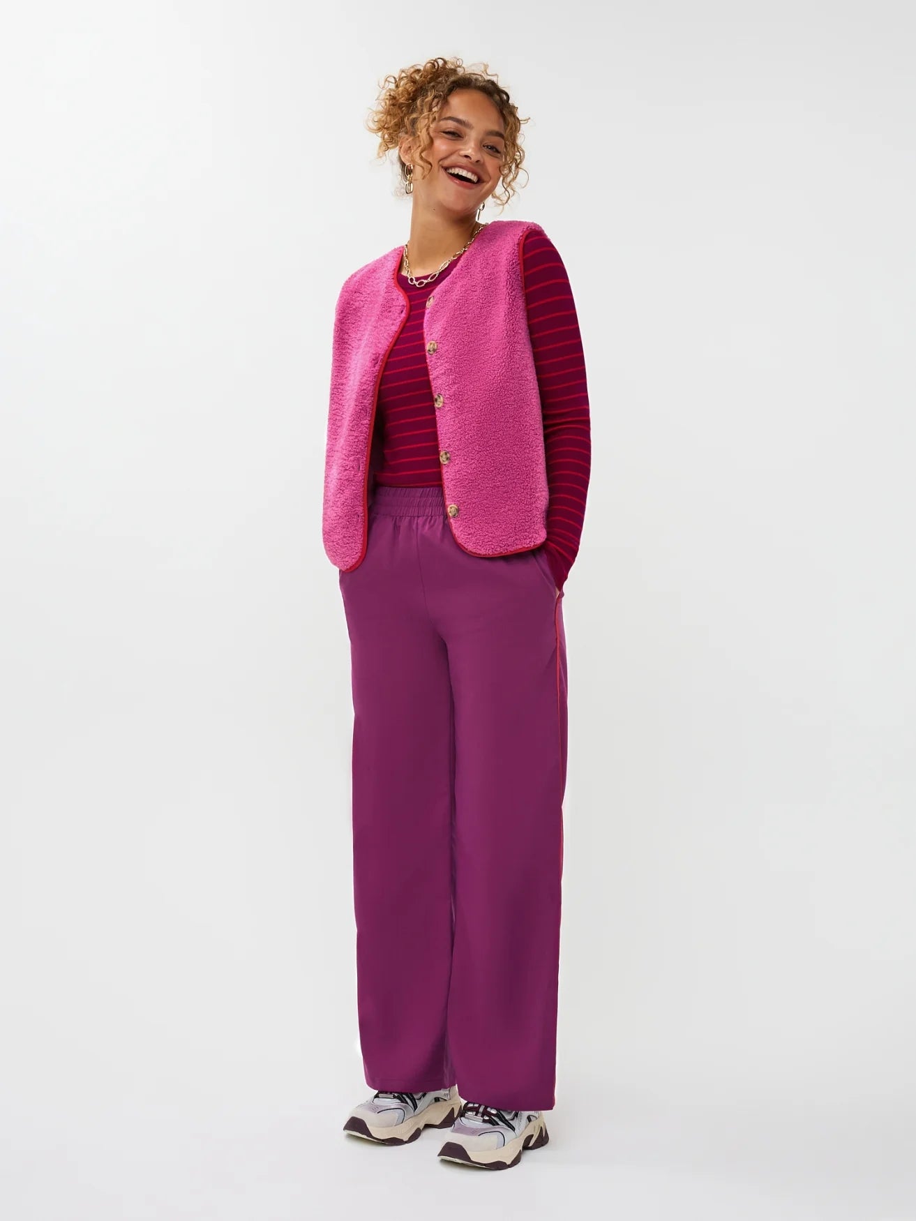 Model draagt het puck gilet van ydende van teddy stof in de kleur fuchsia over de knitted top devina.