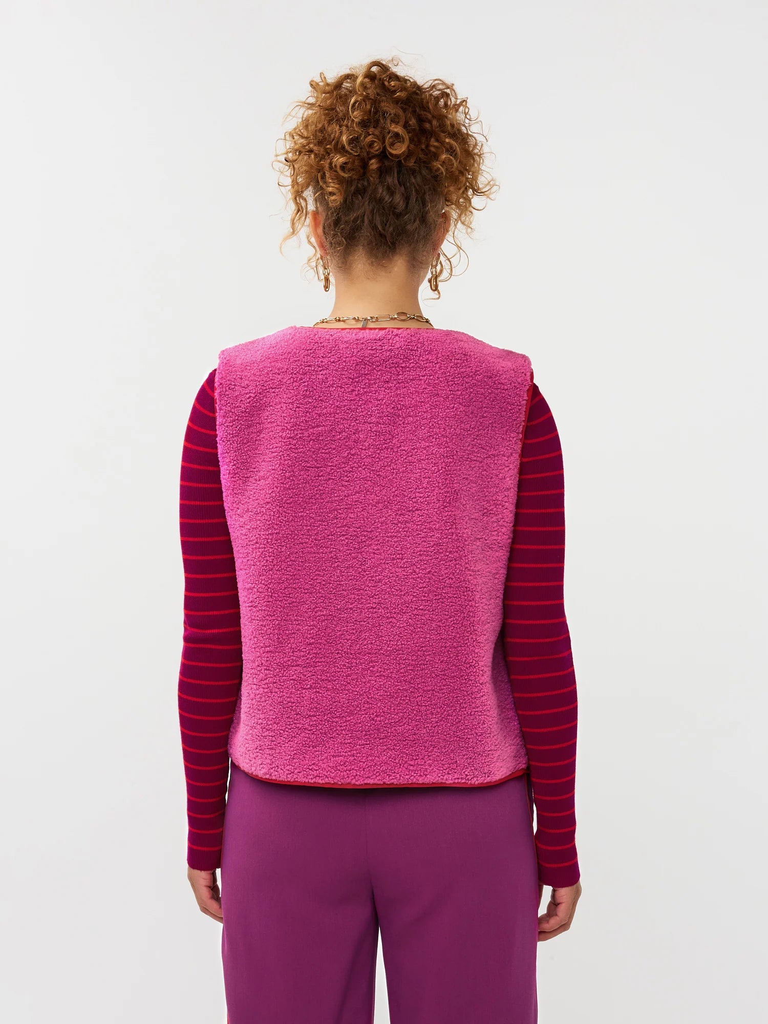 Model draagt het puck gilet van ydende van teddy stof in de kleur fuchsia over de knitted top devina.