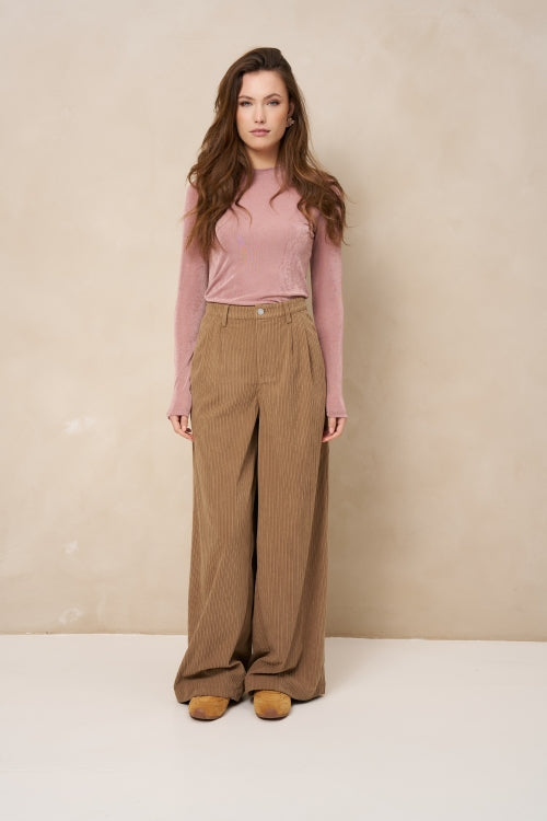 Model in lichtroze longsleeve Jessy met bruine ribcord broek met wijde pijpen | Jo&Co Club