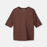 Productfoto van het bruine t-shirt plat gefotografeerd, met studs rond de hals.