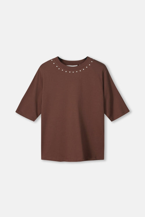 Productfoto van het bruine t-shirt plat gefotografeerd, met studs rond de hals.