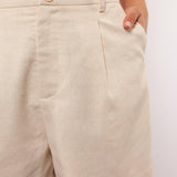 Close-up van de beige Seraphina Shorts met knoopsluiting en steekzakken.

