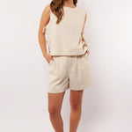 Model draagt de Seraphina Shorts met mouwloze top en oranje sneakers, zomerse outfit.