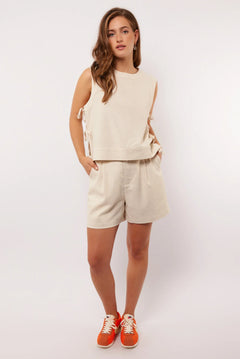 Model draagt de Seraphina Shorts met mouwloze top en oranje sneakers, zomerse outfit.
