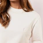 Detail van het witte Fluresk Brix T-shirt met ton-sur-ton geborduurd logo op de borst en subtiele ronde hals.