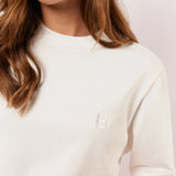 Detail van het witte Fluresk Brix T-shirt met ton-sur-ton geborduurd logo op de borst en subtiele ronde hals.