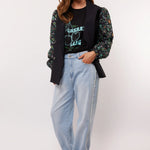 Model draagt de Fluresk Celin Pants in lichtblauw denim met een zwarte Cherry Gang top en gilet.