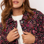 Close-up van model met Fluresk Mirabel Jacket met kleurrijke bloemenprint in roze en paars.