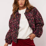 Model draagt het Fluresk Mirabel Jacket open over een witte sweater en bordeauxrode broek.