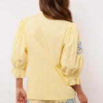Achterkant van de Fluresk Marlowe blouse in geel met pofmouwen en bijpassende short.