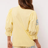 Achterkant van de Fluresk Marlowe blouse in geel met pofmouwen en bijpassende short.