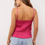 Close-up van de achterkant van de Millicent top in roze satijn met gesmokte stretchstof en verstelbare bandjes, gecombineerd met een denim short.