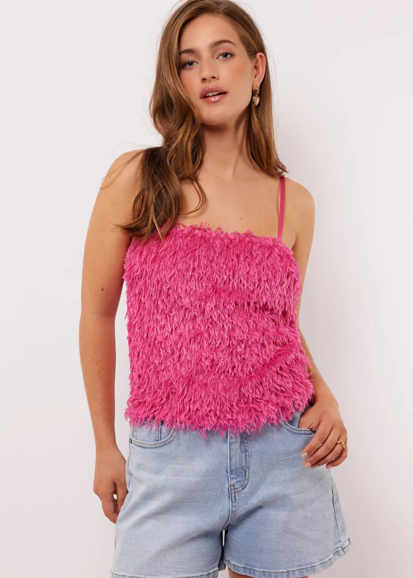 Vrouw draagt de Millicent top in felroze met fluffy textuur aan de voorkant en denim short, voor een speelse zomerse look.