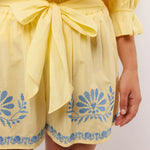 Close-up van de gele Fluresk Saine short met blauwe borduursels en strikceintuur in de taille.