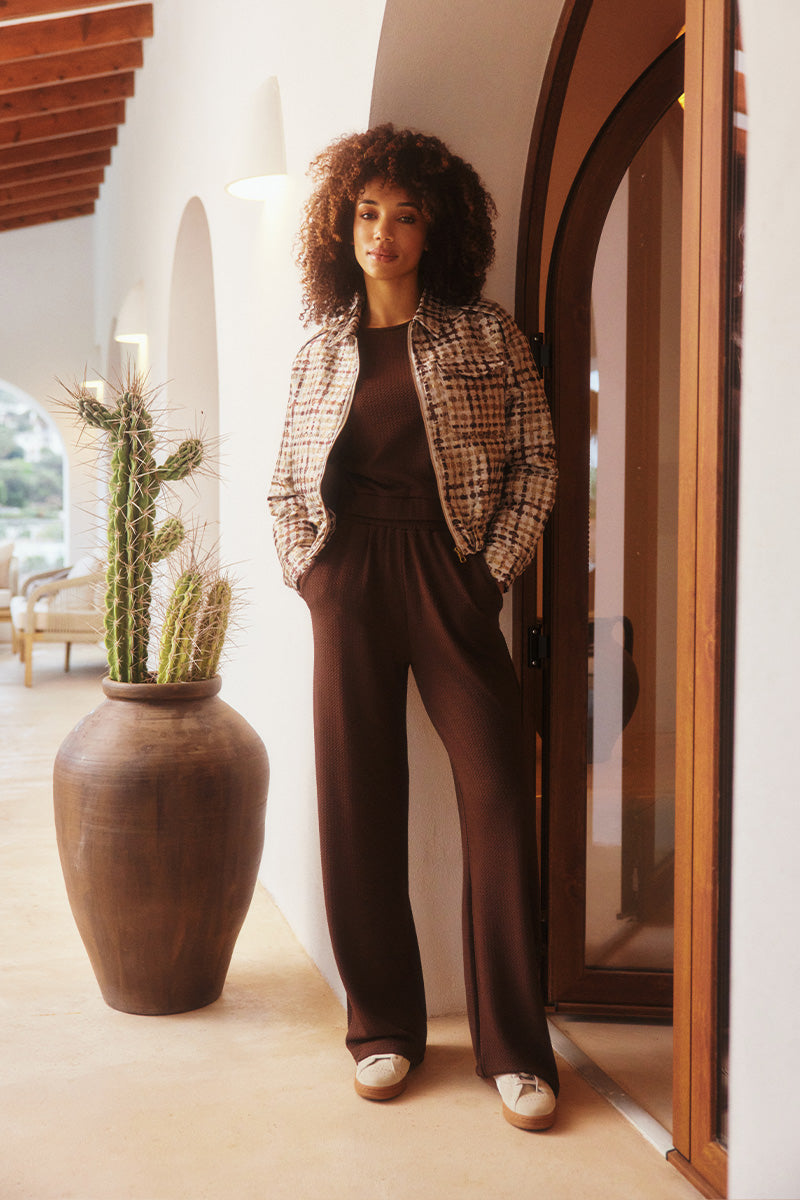 Model draagt de noor jacket van lofty manner in een zomerse setting.
