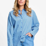 Model draagt de saffierblauwe geruite Beau Check blouse van POM Amsterdam op een lichtblauwe jeans.