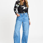 Model draagt de mid blue wijde jeans Jacky van POM Amsterdam met studs langs de zijnaad.