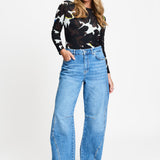 Model draagt de mid blue wijde jeans Jacky van POM Amsterdam met studs langs de zijnaad.