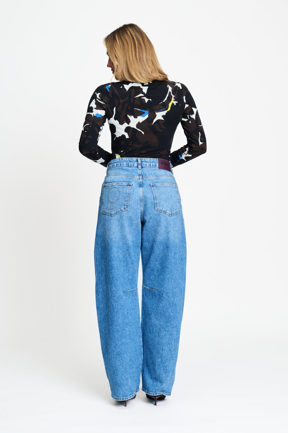 Achterkant van de mid blue jeans met vijf zakken en wijde pijpen.
