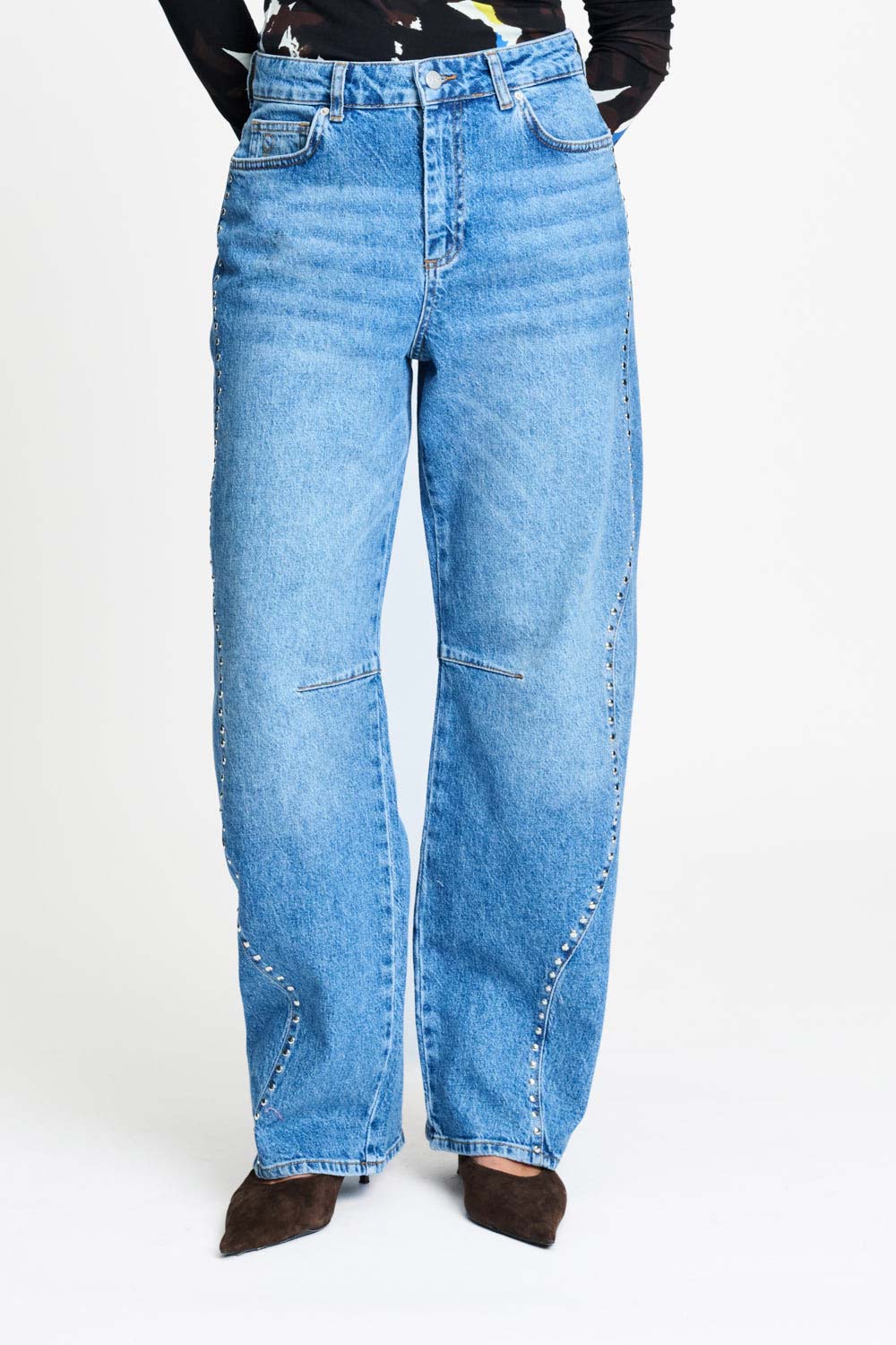 De brede pijpen van de jeans van dichtbij, gedragen op een hak.