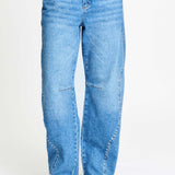 De brede pijpen van de jeans van dichtbij, gedragen op een hak.