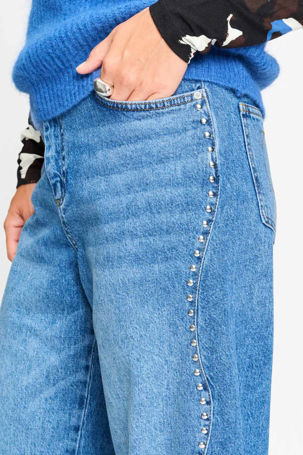 Detailfoto van de zilverkleurige studs langs de zijnaad van de jeans.