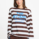 Model draagt de bruin met witte gestreepte longsleeve van POM Amsterdam met blauwe print.