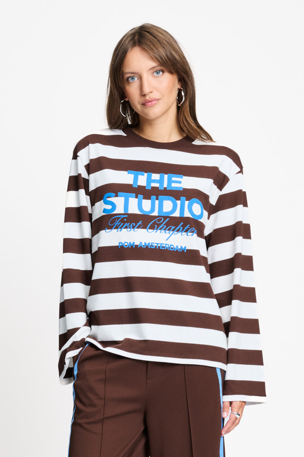 Model draagt de bruin met witte gestreepte longsleeve van POM Amsterdam met blauwe print.