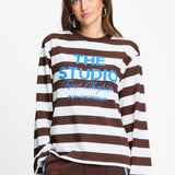 Model draagt de bruin met witte gestreepte longsleeve van POM Amsterdam met blauwe print.