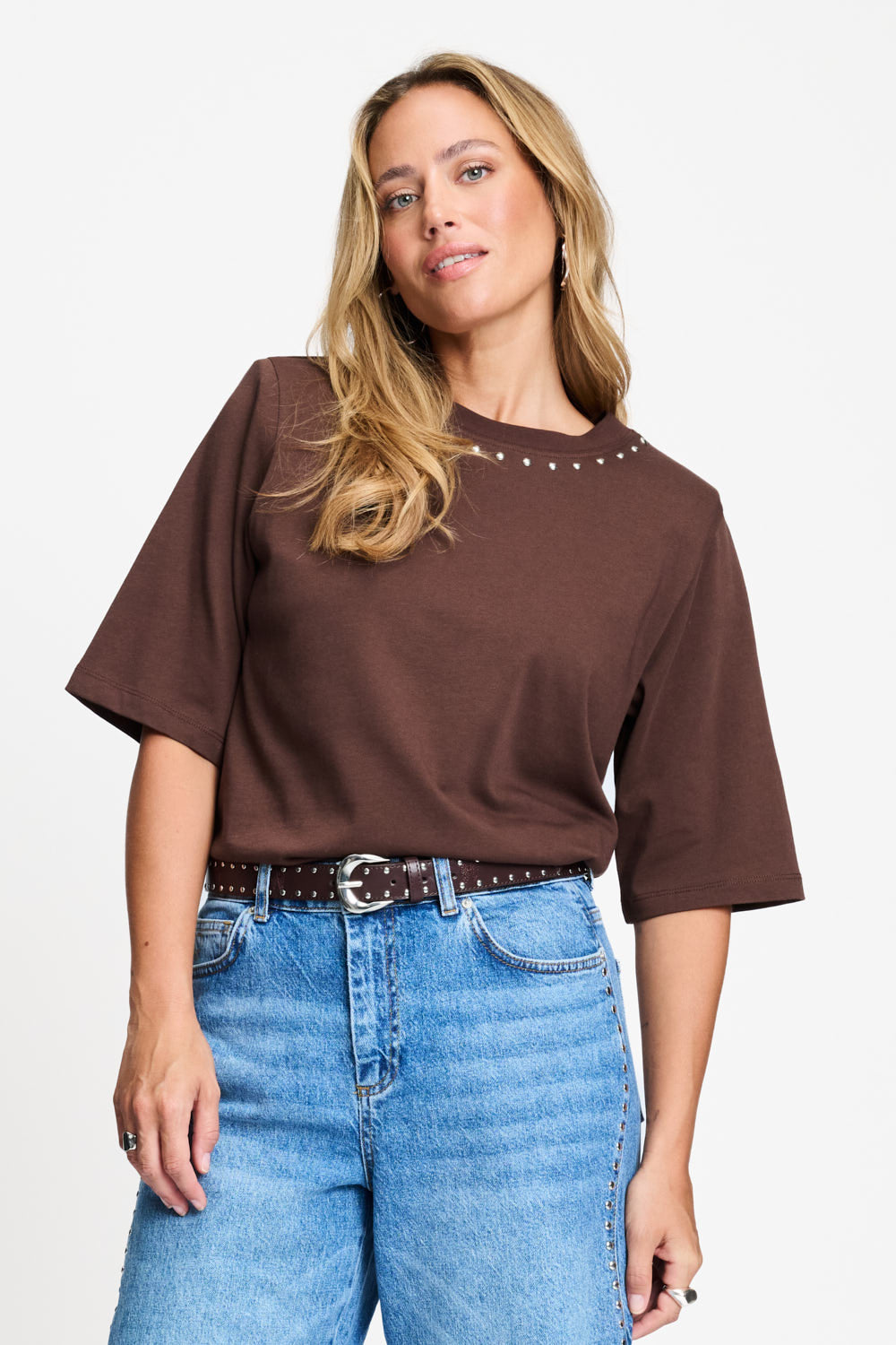 Model draagt het chocoladebruine t-shirt Taylor van POM Amsterdam op een lichte jeans.