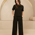 model draagt de dora trouser en de eva top van lofty amnner, het is een co-ord set in het zwart met glinstering.