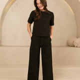 model draagt de dora trouser en de eva top van lofty amnner, het is een co-ord set in het zwart met glinstering.