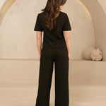 model draagt de dora trouser en de eva top van lofty amnner, het is een co-ord set in het zwart met glinstering.