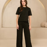 model draagt de dora trouser en de eva top van lofty amnner, het is een co-ord set in het zwart met glinstering.