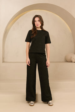 model draagt de dora trouser en de eva top van lofty amnner, het is een co-ord set in het zwart met glinstering.