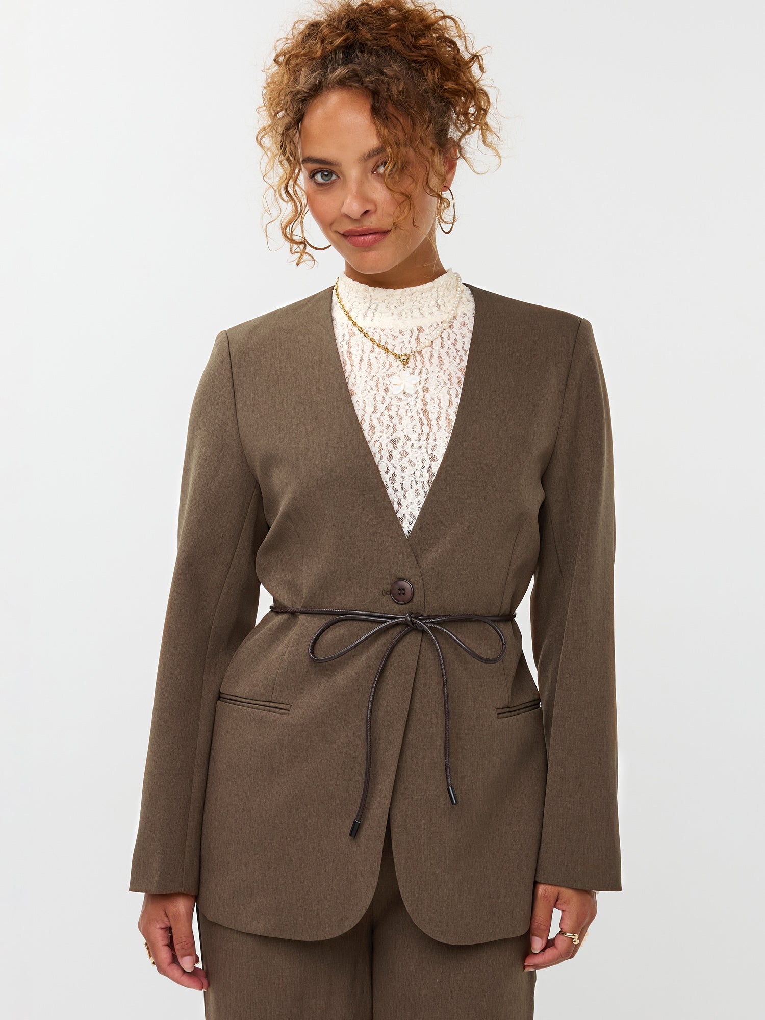 model draagt de ydence lexie blazer in de kleir mud met een zwart ceintuur.