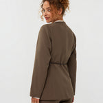 model draagt de ydence lexie blazer in de kleir mud met een zwart ceintuur, achter aanzicht.