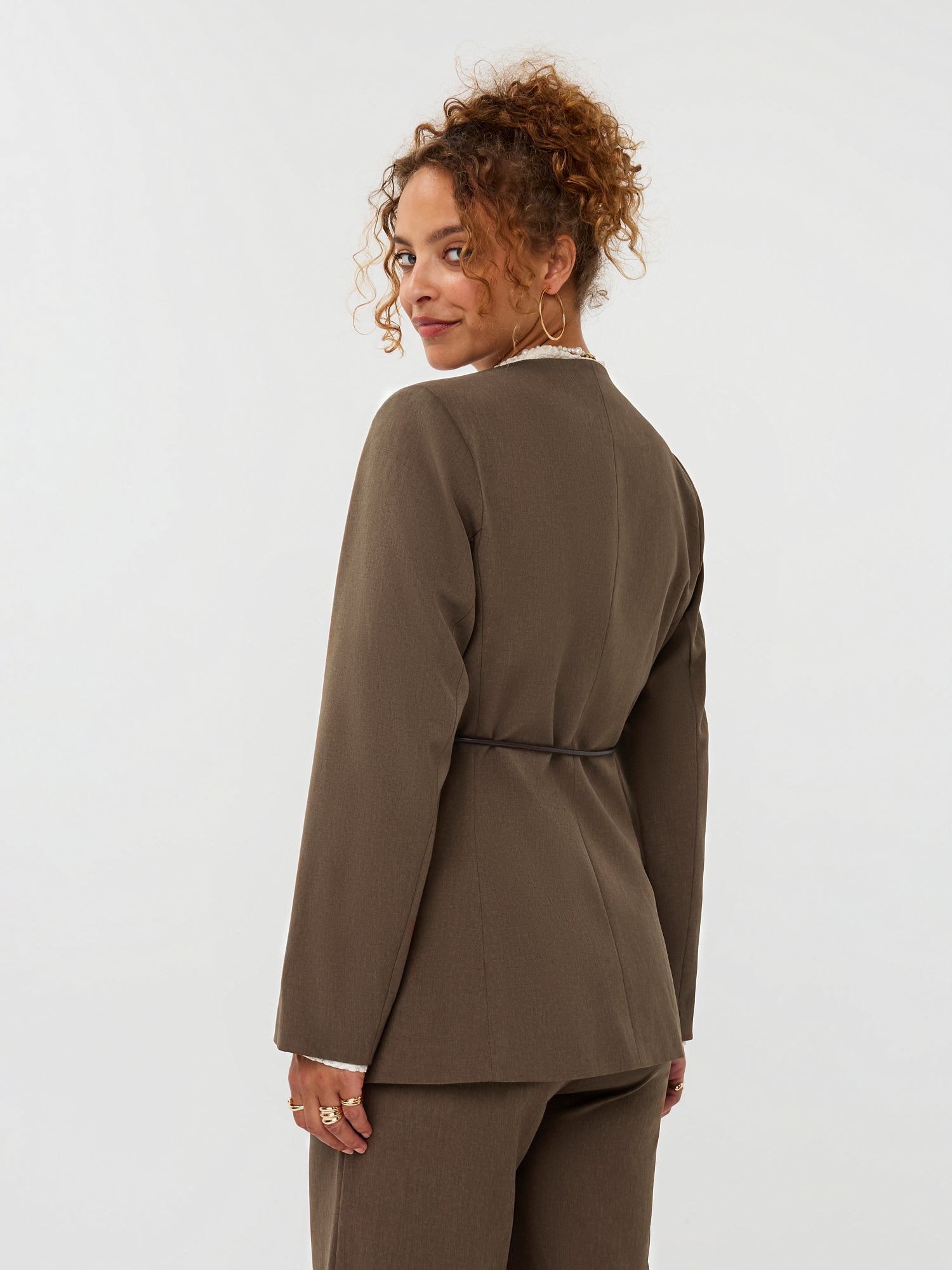 model draagt de ydence lexie blazer in de kleir mud met een zwart ceintuur, achter aanzicht.