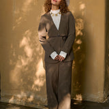 model draagt de ydence lexie blazer in de kleir mud met een zwart ceintuur en de yade pants in een zonnige herst achtige setting.