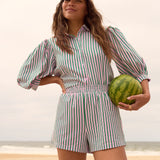 Model draagt de Annie blouse en Belle short van Ydence als co-ord set op het strand – zomerse look met streepjesprint.